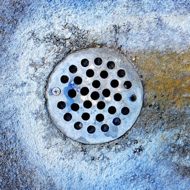 commercial drain with build-up around the base.